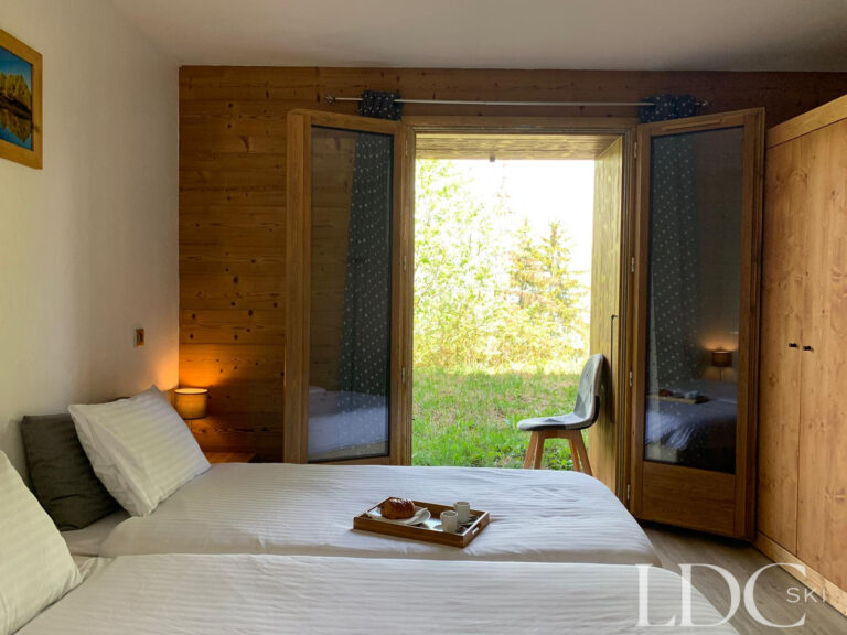 Double bedroom with large window and timber detailing at Chalet Edelweiss in Les Coches