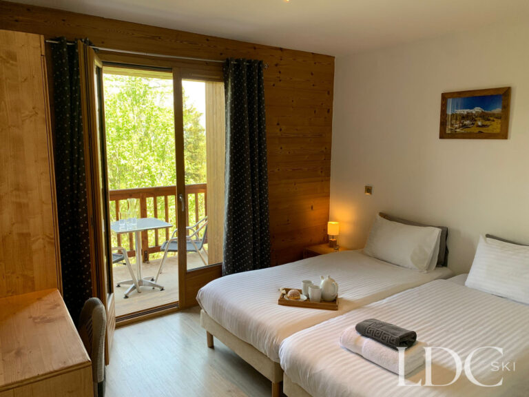 Twin bedroom with doors opening onto the balcony at Chalet Edelweiss