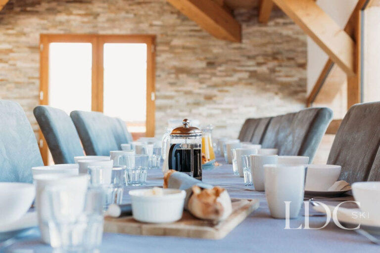 Chalet dining room with exposed stone wall and timber beams at Chalet Edelweiss in Les Coches