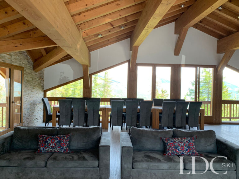 Spacious chalet lounge with vaulted timber ceiling and large windows at Chalet Edelweiss in Les Coches