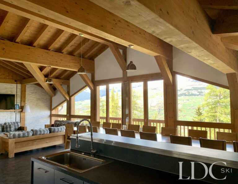 Open-plan dining room and kitchen with exposed timber beams at Chalet Flocon