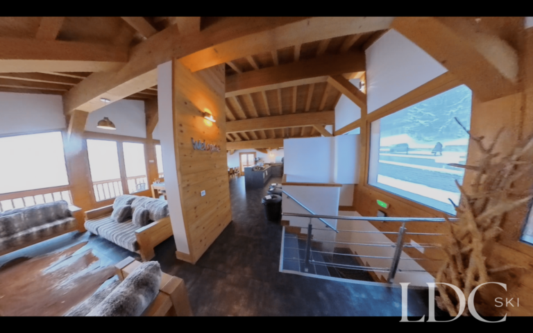 Open-plan timber-framed lounge with large windows and mountain views at Chalet Flocon