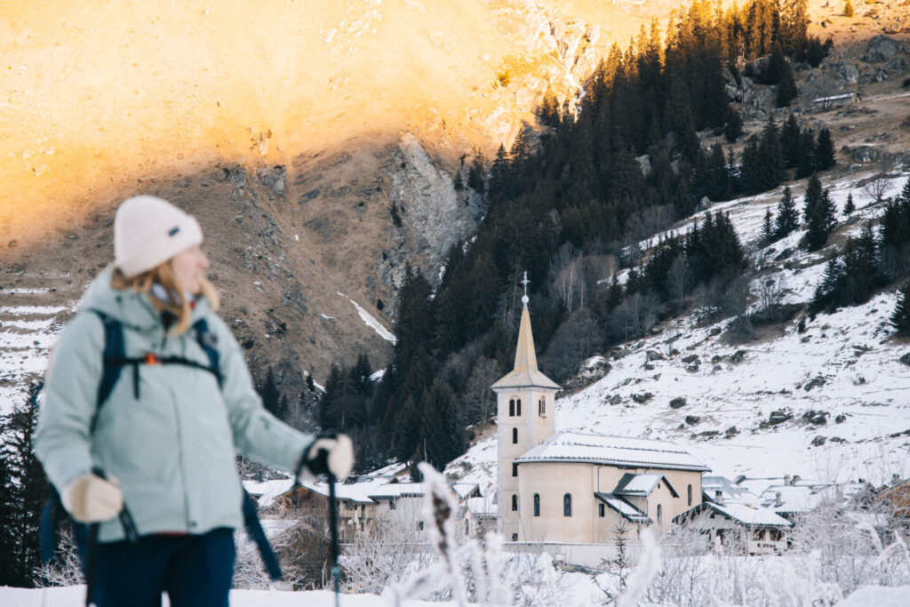 Winter walker in the snow beside the village church in Champagny-le-Haut – © Clara Fotomania / La Plagne