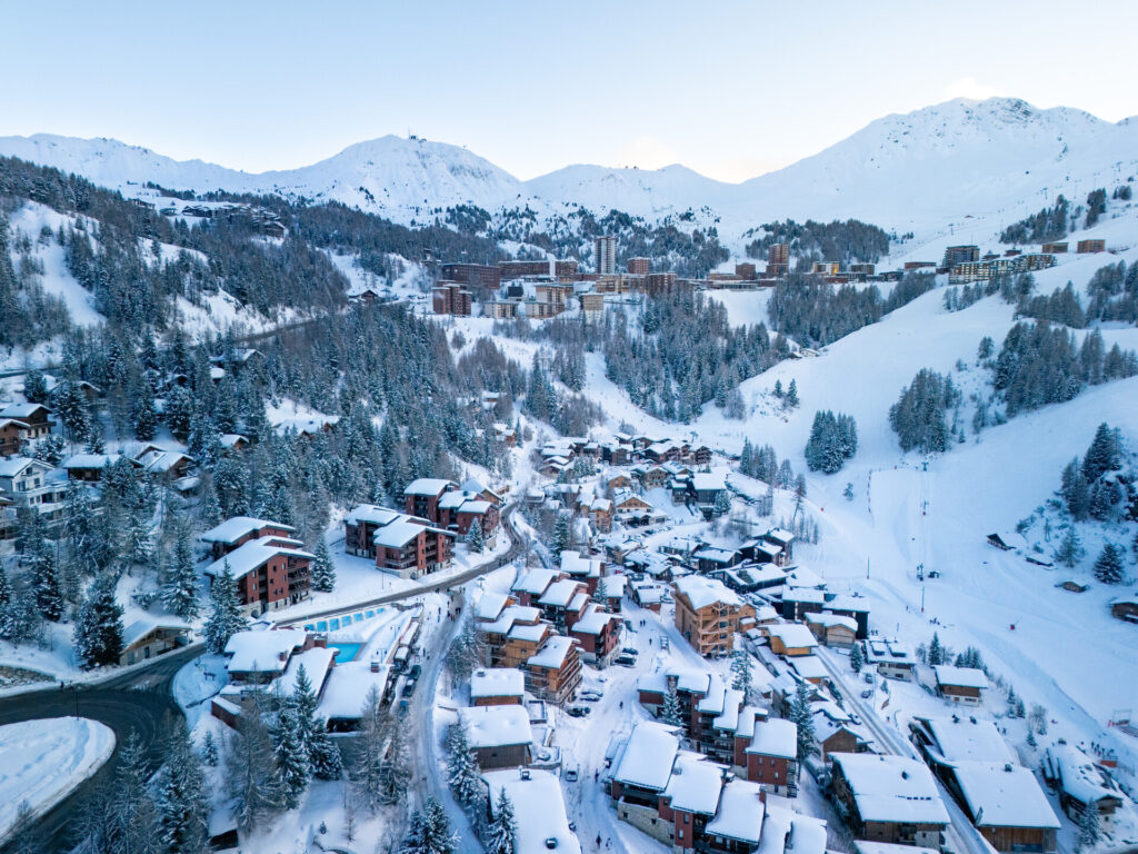 Snow-covered buildings and forest in Plagne 1800 – © Brendan Le Peru / La Plagne