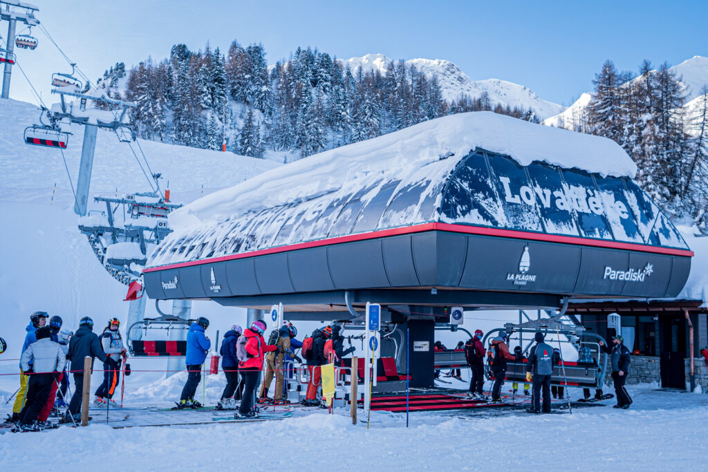 Skiers gathering at a chairlift on a snowy day in La Plagne – © JNJ Photo / La Plagne