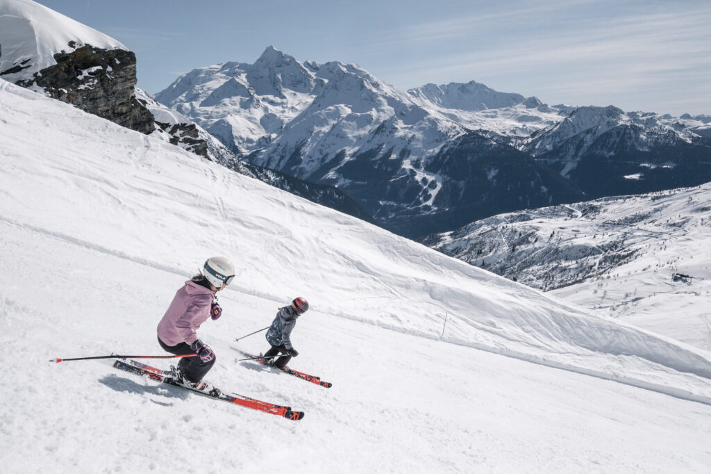 Adult and child skiing together on a wide snowy piste in La Rosière