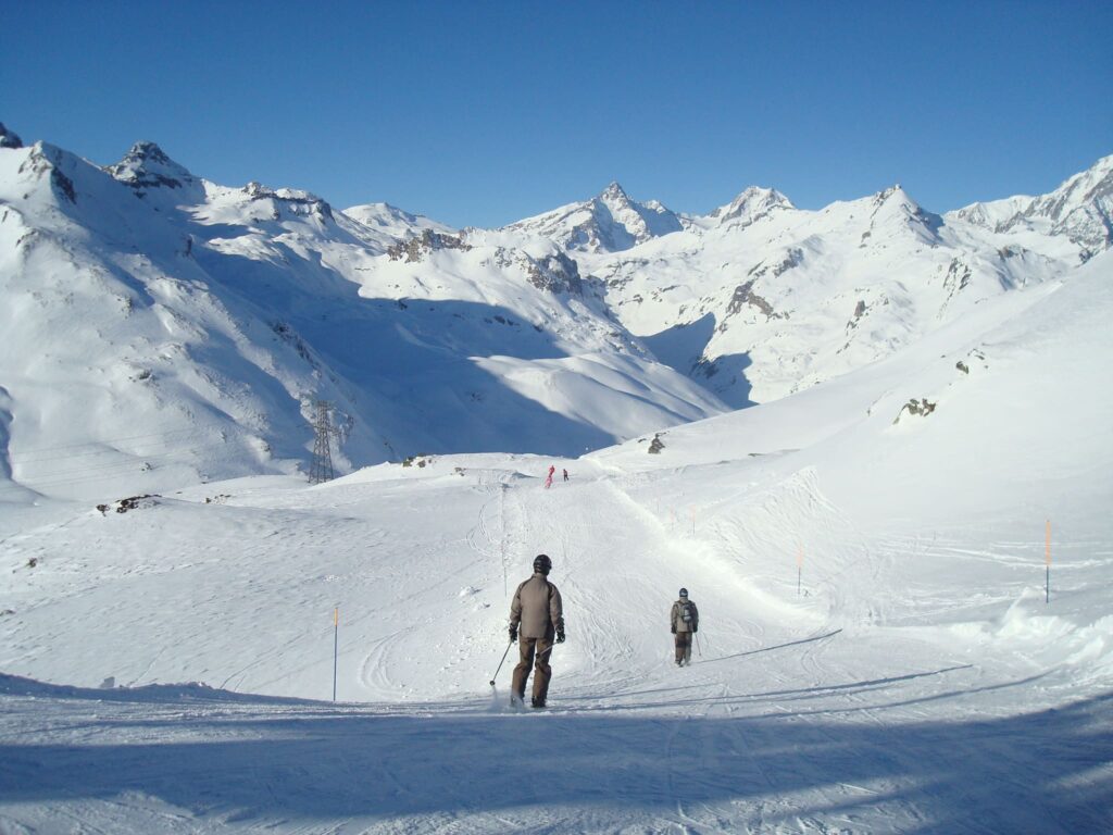 Skiers crossing a snowy slope surrounded by mountain scenery in La Rosière
