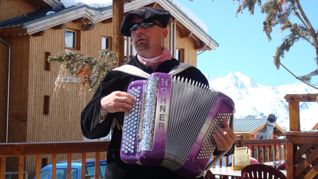 Accordion player performing outside a traditional chalet in La Rosière