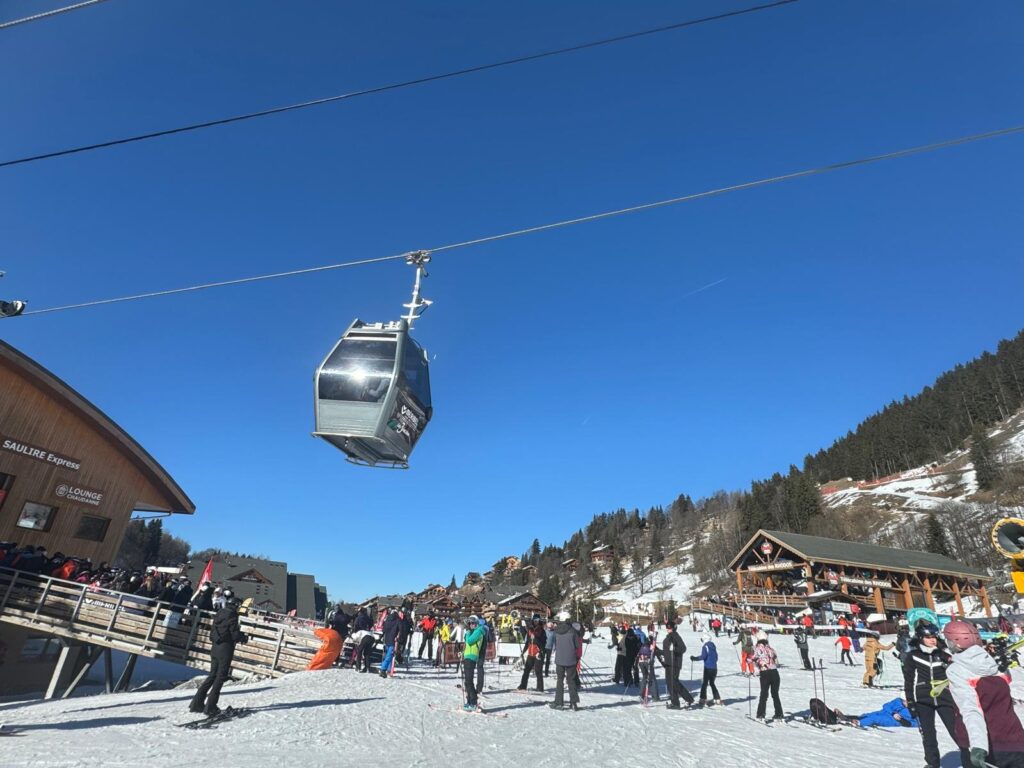 Gondola travelling above skiers in the Méribel ski area