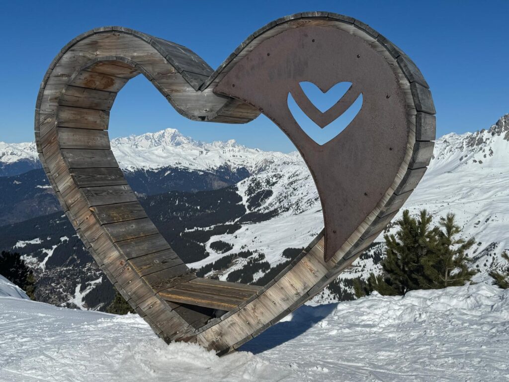 Wooden Méribel heart framing the snow-covered mountain landscape