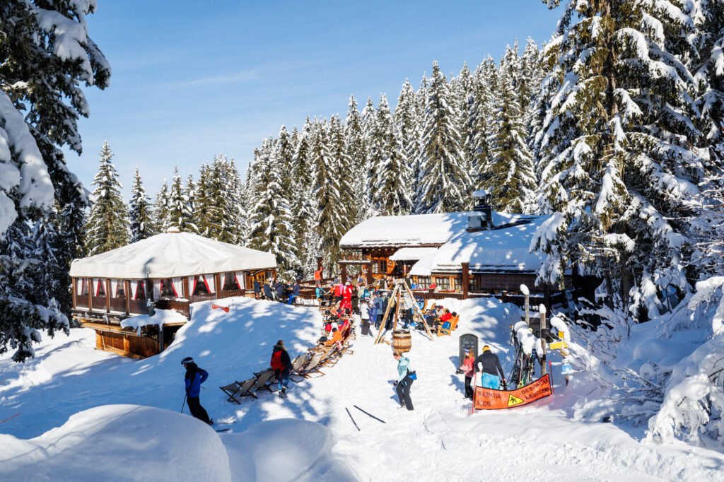 Skiers enjoying a mountain restaurant surrounded by snowy forest in Méribel