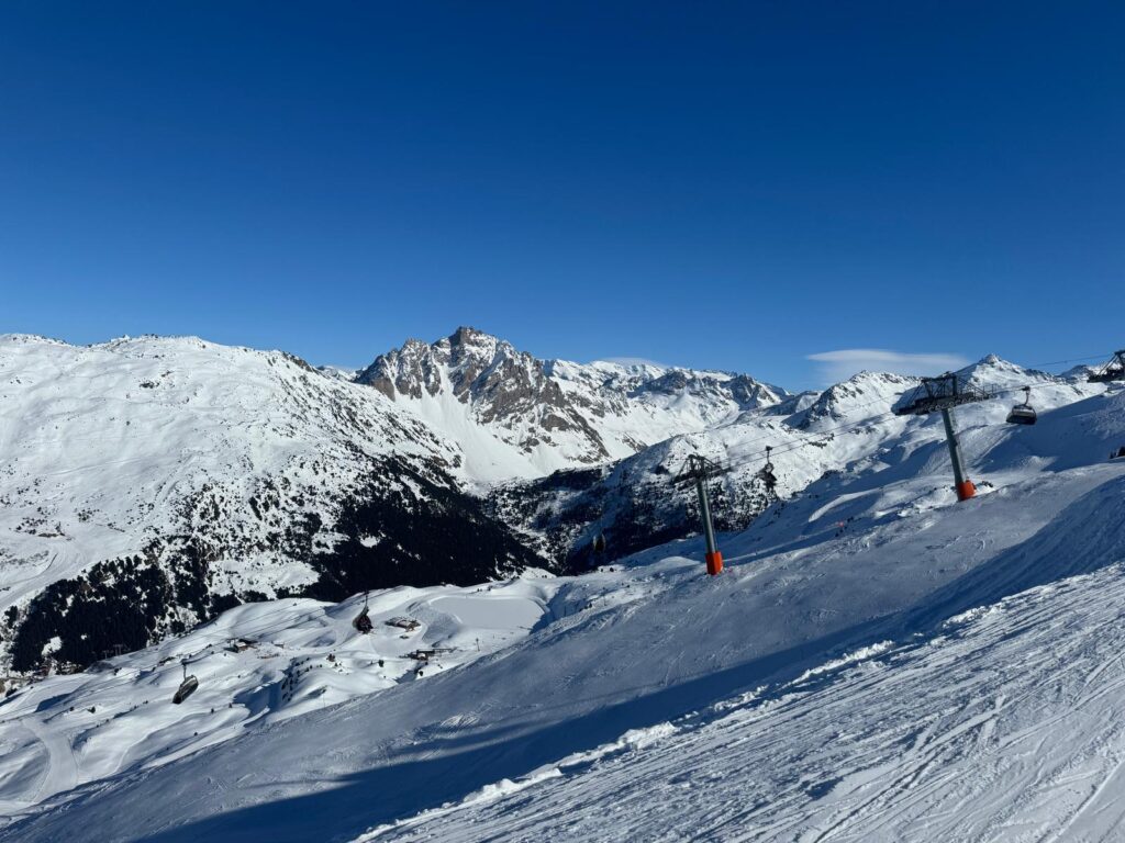 Skier on a sunny piste surrounded by snowy mountain scenery in Méribel