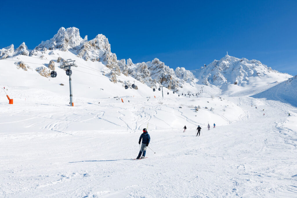 Skier on a sunny Méribel piste beneath dramatic mountain peaks