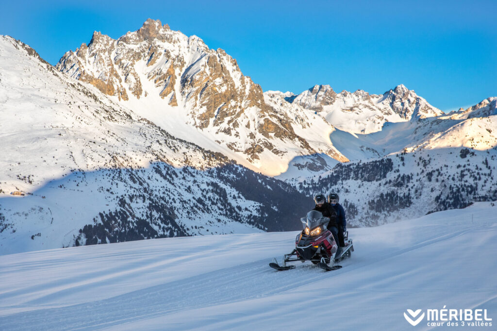Snowmobile crossing the snowy mountains above Méribel