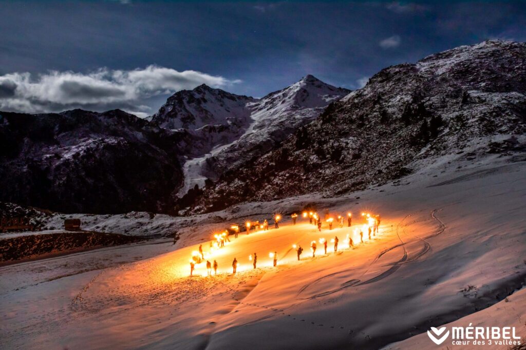 Torchlight ski descent illuminating the slopes of Méribel at night