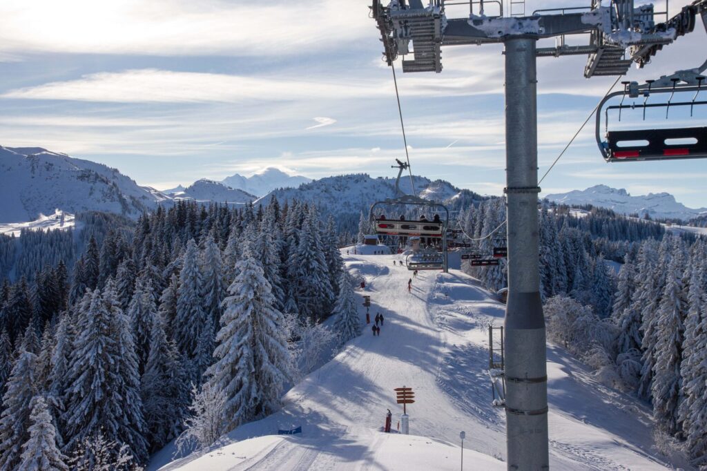 Chairlift travelling above snowy pistes and forest in Morzine
