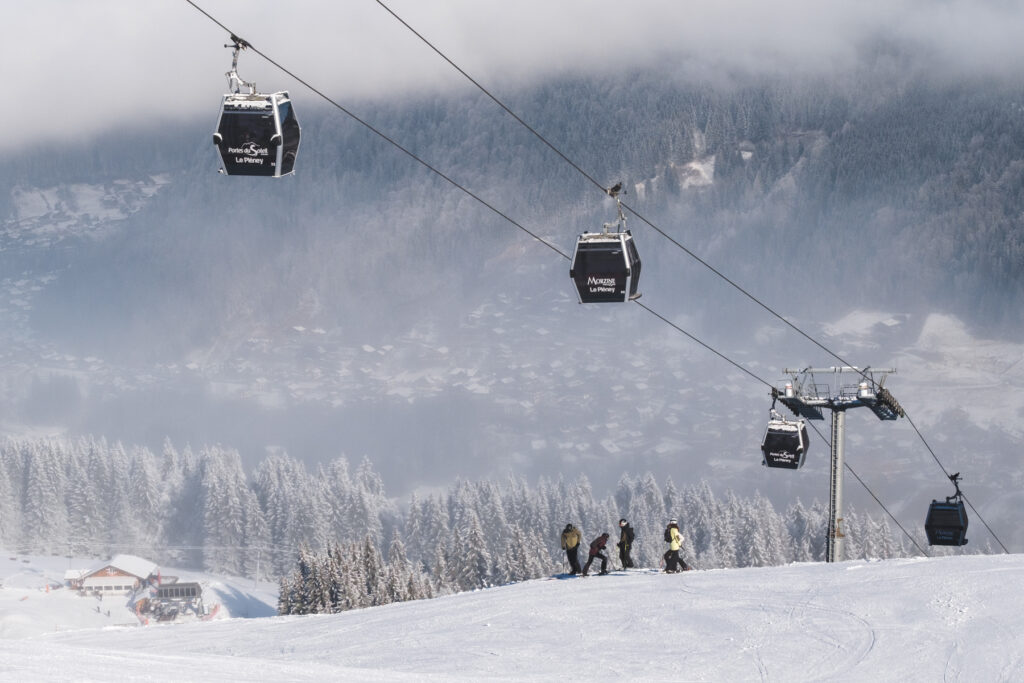 Gondola cabins travelling above a snowy piste in Morzine