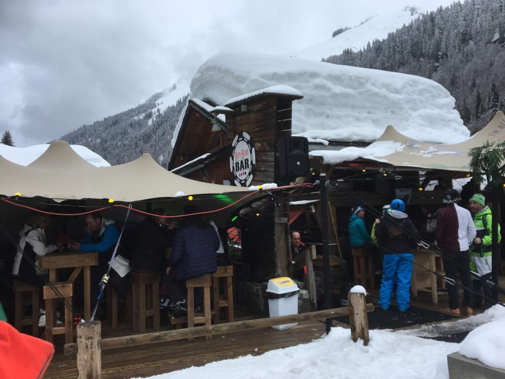 Skiers enjoying après ski outside a snow-covered mountain bar