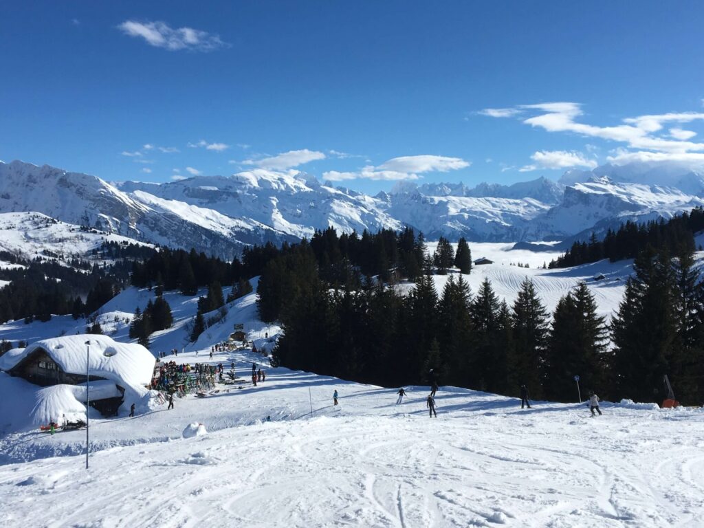 Snow-covered chalets and pistes surrounded by mountain scenery