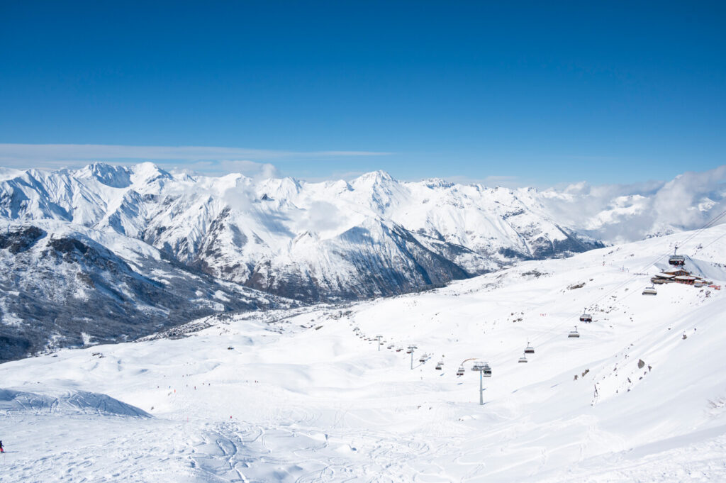 Skiers outside a mountain restaurant overlooking the snowy peaks above St Martin de Belleville