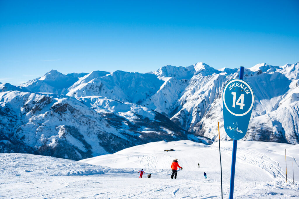 Skiers on Piste 14 with panoramic mountain views above St Martin de Belleville
