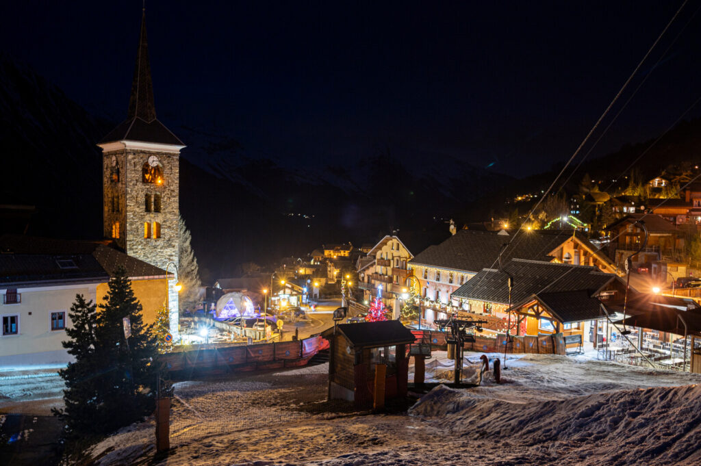Church and village centre illuminated on a snowy winter evening in St Martin de Belleville