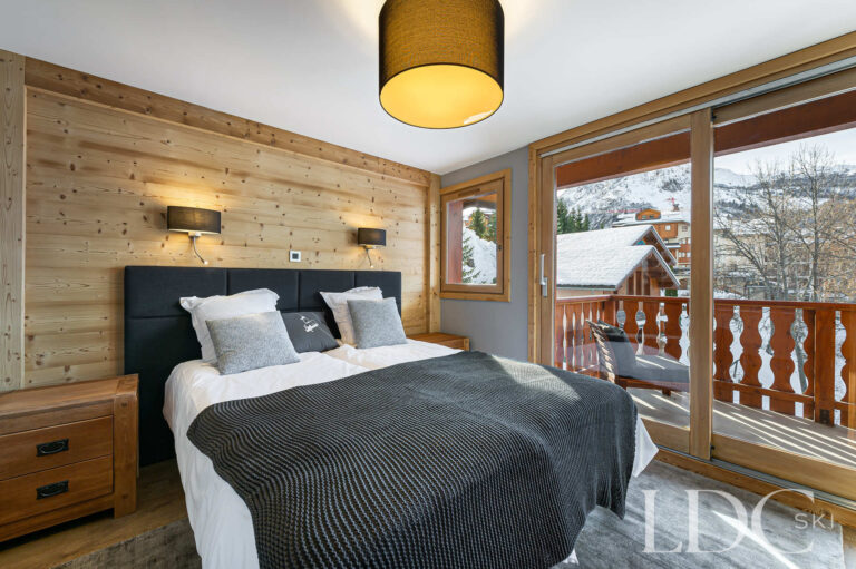 Double bedroom at Prestige No.5 with timber walls and doors opening onto the balcony