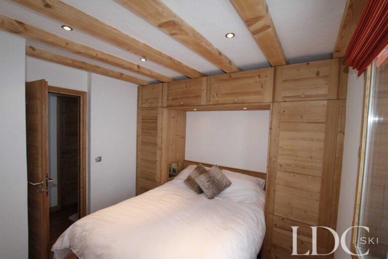 Biollay 53 double bedroom with built-in timber storage and exposed beams