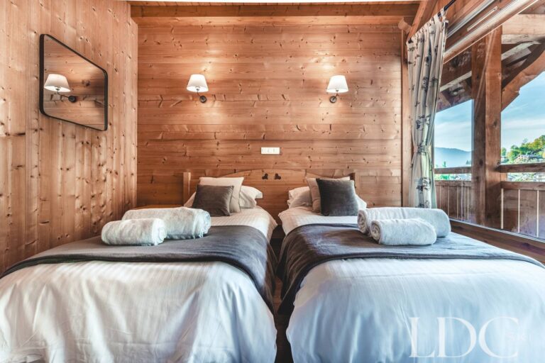 Twin bedroom with traditional timber walls at Cairn Lodge in Morzine