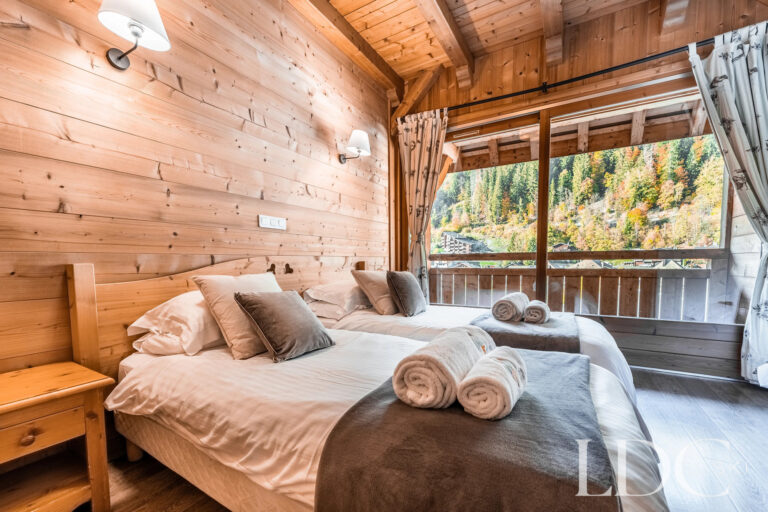 Double bedroom with large window overlooking the mountains at Cairn Lodge in Morzine