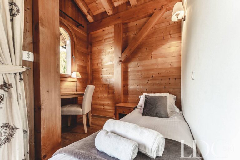 Cosy bedroom with seating area and timber walls at Cairn Lodge