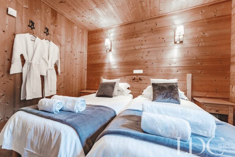 Spacious twin bedroom with traditional timber walls at Cairn Lodge
