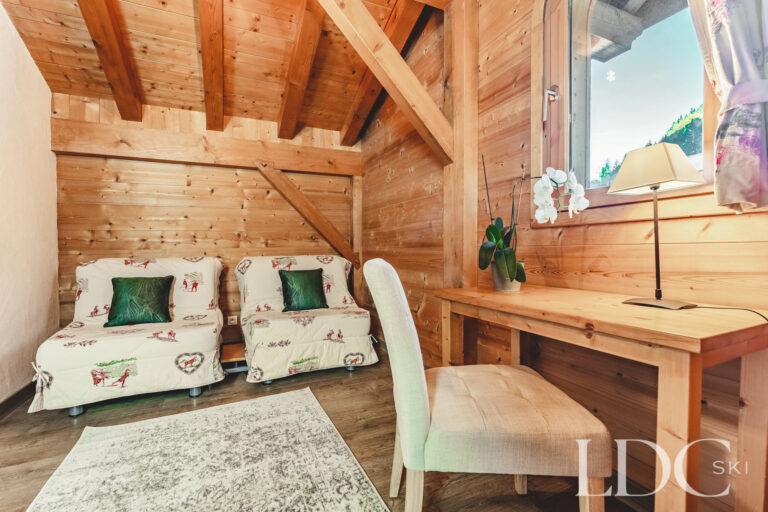 Timber-lined bedroom with day bed and desk at Cairn Lodge