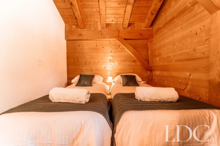 Twin bedroom beneath a sloping timber ceiling at Cairn Lodge