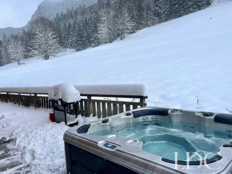 Outdoor hot tub overlooking the snowy mountains at Cairn Lodge in Morzine