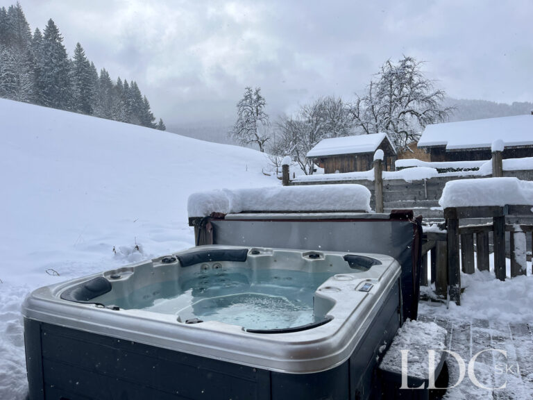 Outdoor hot tub surrounded by snow at Cairn Lodge in Morzine