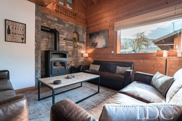 Cosy lounge with wood-burning stove and mountain views at Cairn Lodge in Morzine