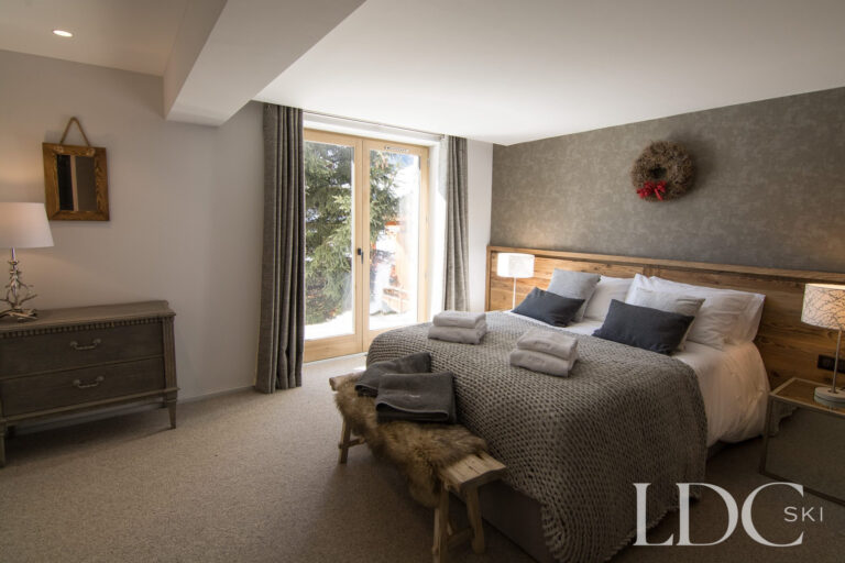 Spacious double bedroom with wooden headboard and large window at Chalet Astilla in St Martin de Belleville