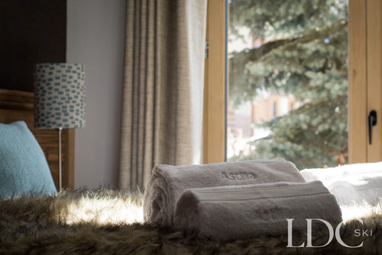 Towels laid out on a fur throw beside the window in a bedroom at Chalet Astilla in St Martin de Belleville