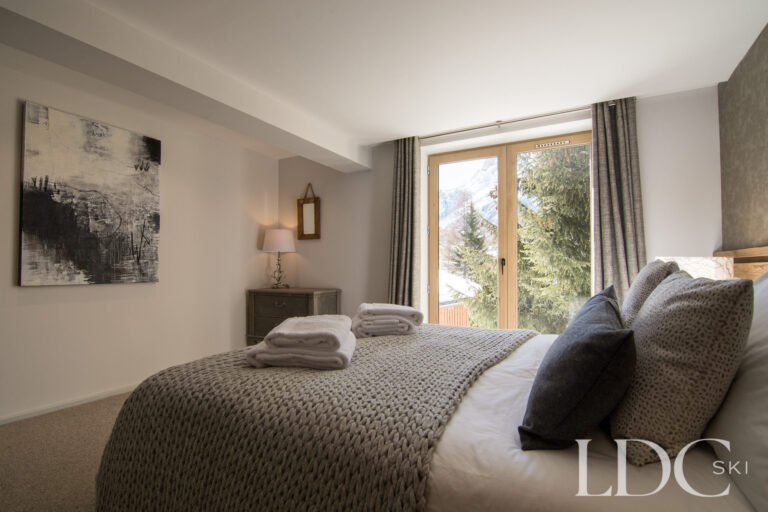 Double bedroom with large window overlooking the snowy mountains at Chalet Astilla in St Martin de Belleville