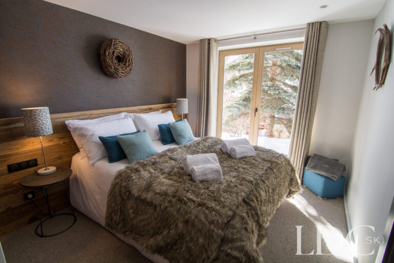 Cosy double bedroom with fur throw and large window at Chalet Astilla in St Martin de Belleville