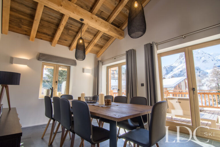 Spacious dining area with exposed timber ceiling and mountain views at Chalet Astilla in St Martin de Belleville