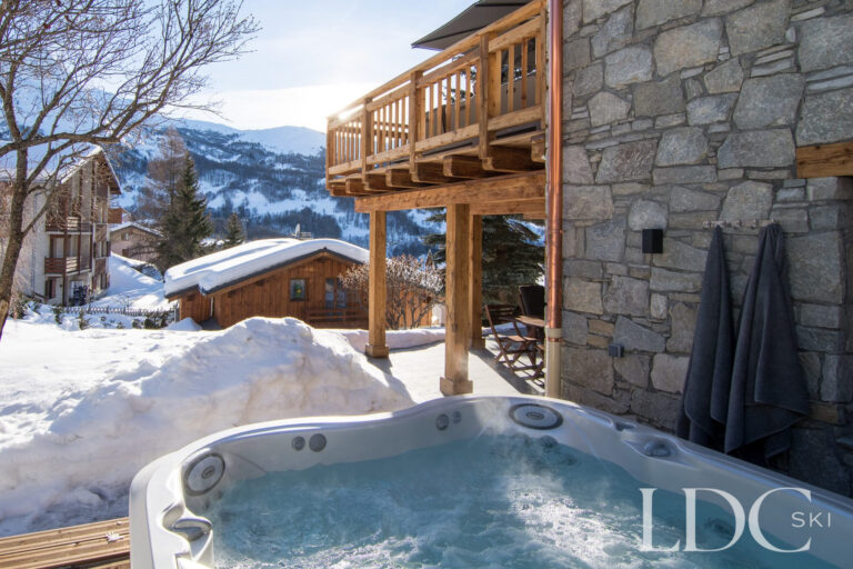 Outdoor hot tub surrounded by snow with mountain views at Chalet Astilla in St Martin de Belleville