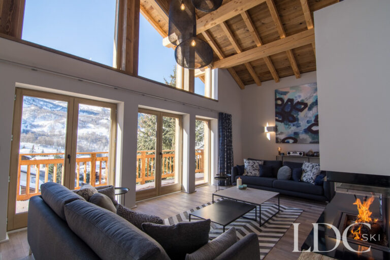 Spacious lounge at Chalet Astilla with contemporary fireplace, large windows and mountain views in St Martin de Belleville