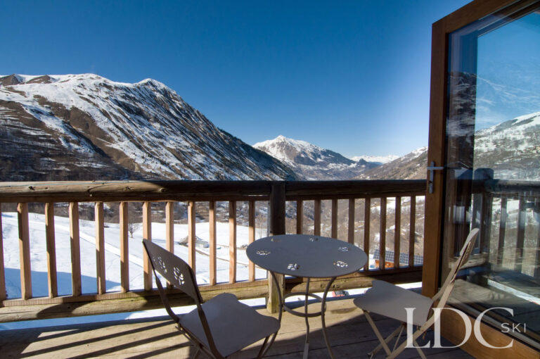 Sunny balcony at Chalet Ann with table, chairs and mountain views