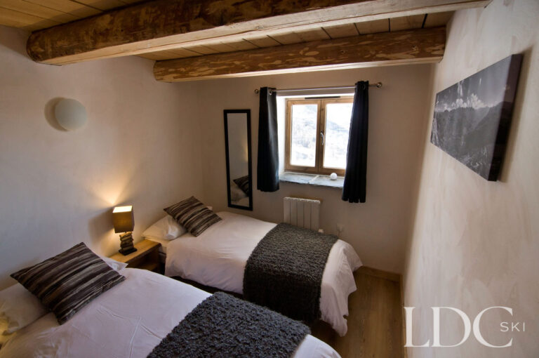Twin bedroom at Chalet Ann with exposed timber ceiling and mountain-style décor