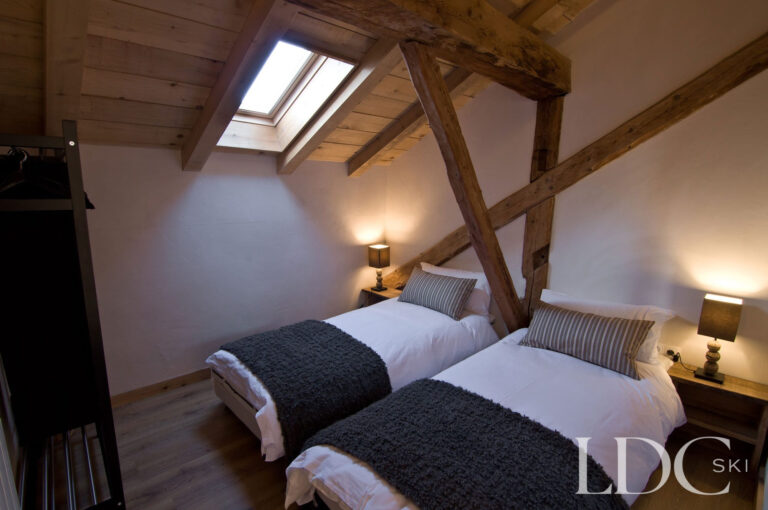 Twin bedroom at Chalet Ann beneath a vaulted timber ceiling with roof windows