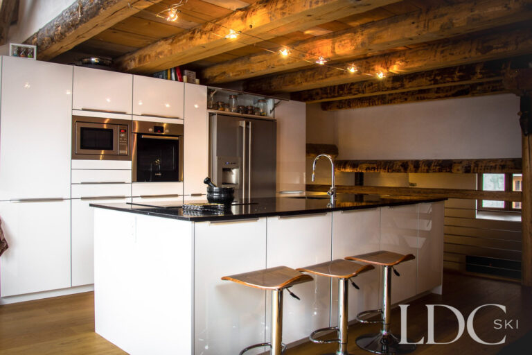 Modern open-plan kitchen at Chalet Ann with island breakfast bar and exposed timber ceiling