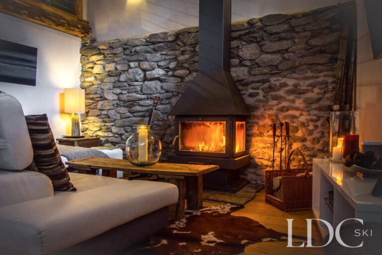 Cosy lounge at Chalet Ann with stone walls, sofas and a central log-burning fireplace