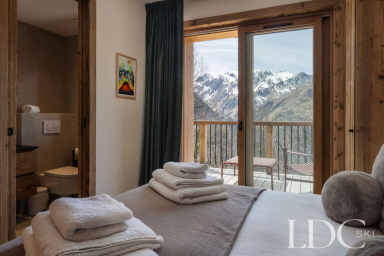 Chalet Aurea bedroom opening onto a balcony with mountain views